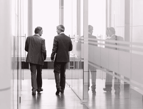 Two business professionals discussing communication strategies while walking through a modern office corridor